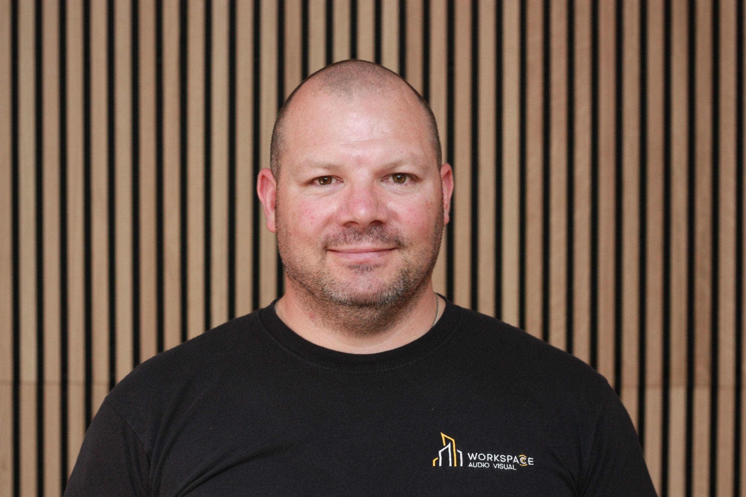 man in a black shirt standing in front of a wall